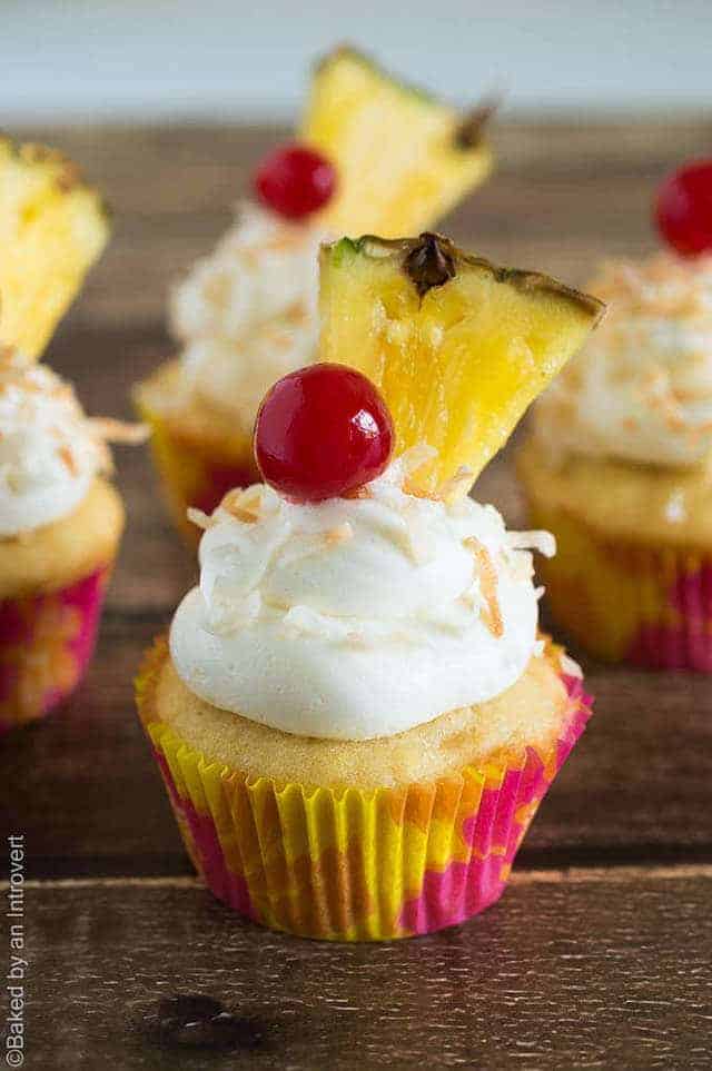 Side view of pina colada cupcakes on a wood background.