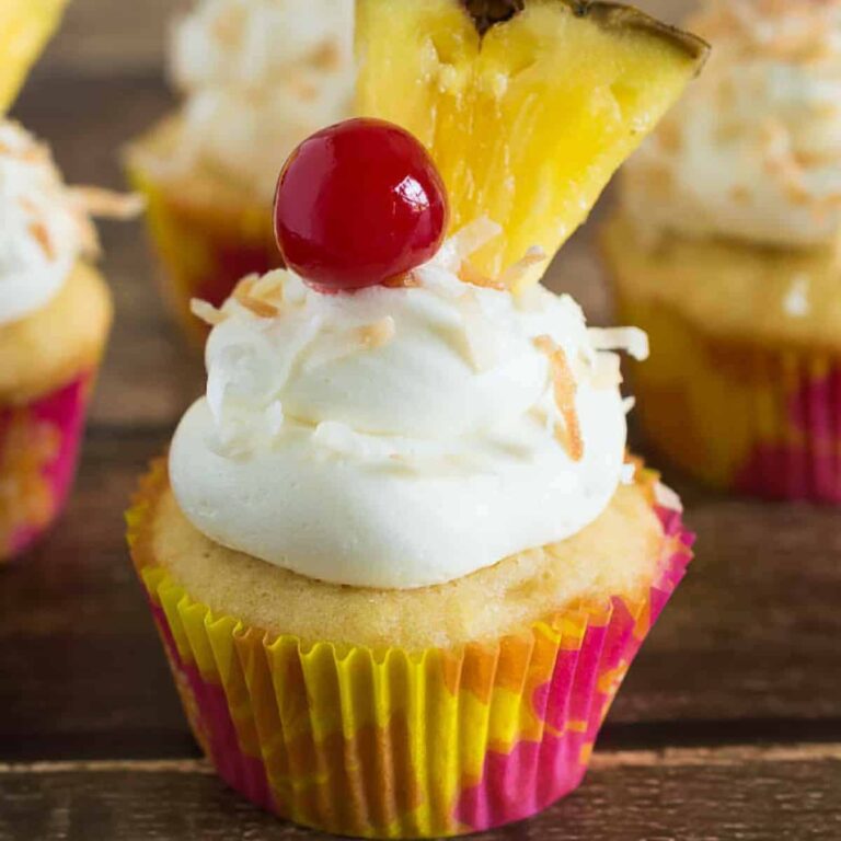 Side view of pina colada cupcakes on a wood background.