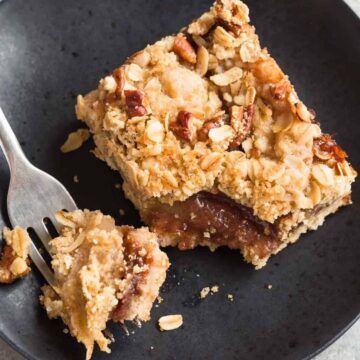 Apple Streusel Bar on a black plate with a fork taking a bit out of it.