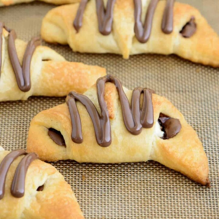 Angled view of Nutella cream cheese crescent rolls on a baking sheet lined with a silicone mat.
