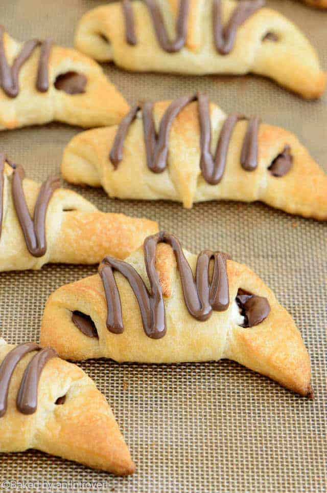 Angled view of Nutella cream cheese crescent rolls on a baking sheet lined with a silicone mat.