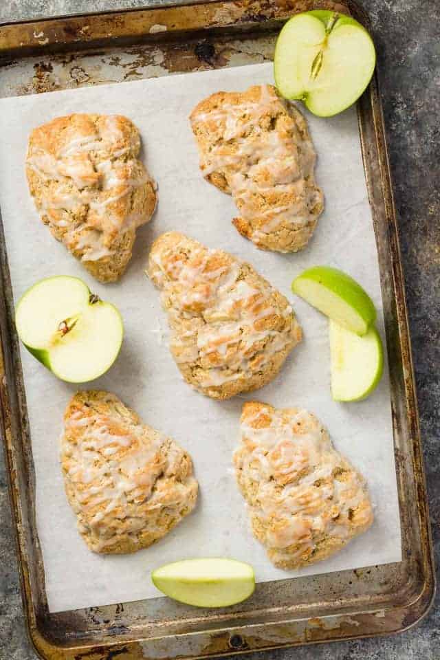 Apple cinnamon scones and slices of green apple on a baking sheet lined with parchment paper.