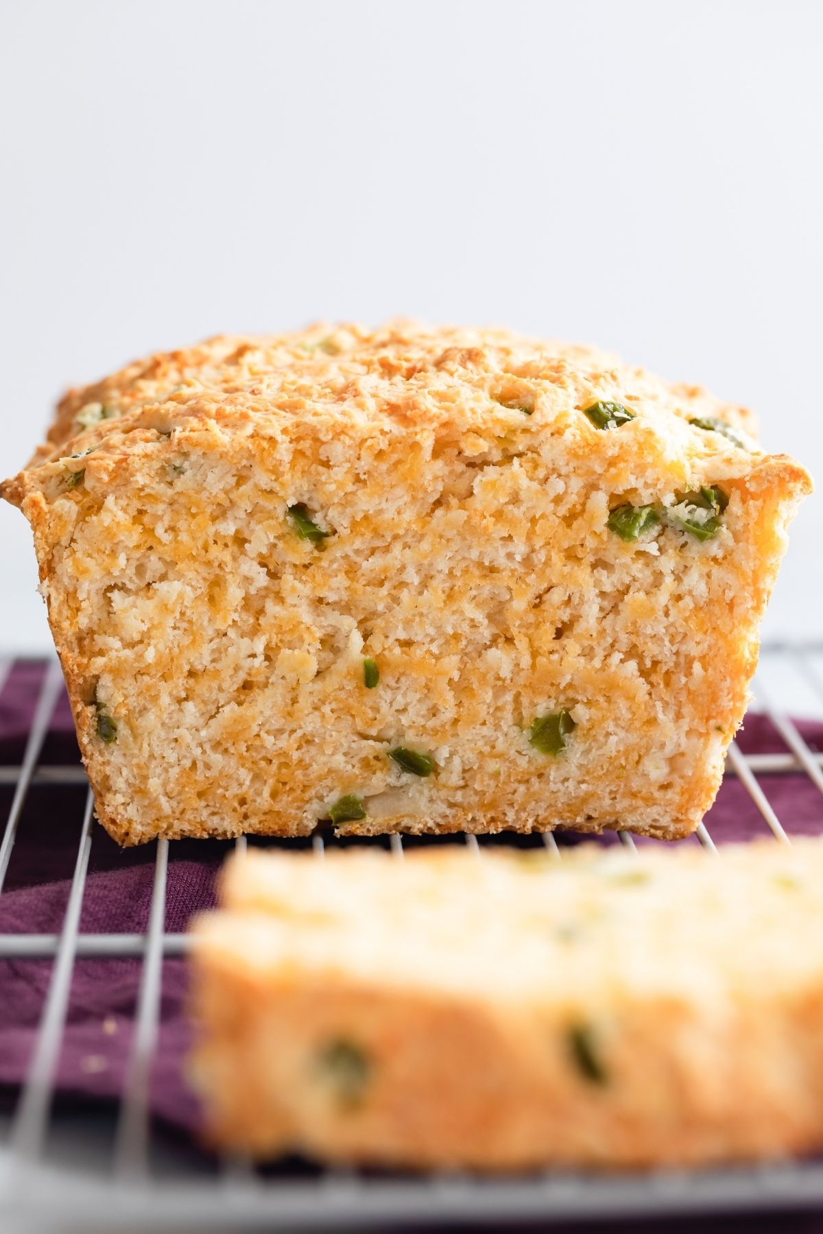 cheddar jalapeno buttermilk bread on a wire rack with a slice cut out