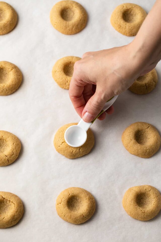 A teaspoon pressing indentations in thumbprint cookies