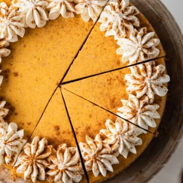 Overhead of pumpkin cheesecake topped with whipped cream and cinnamon