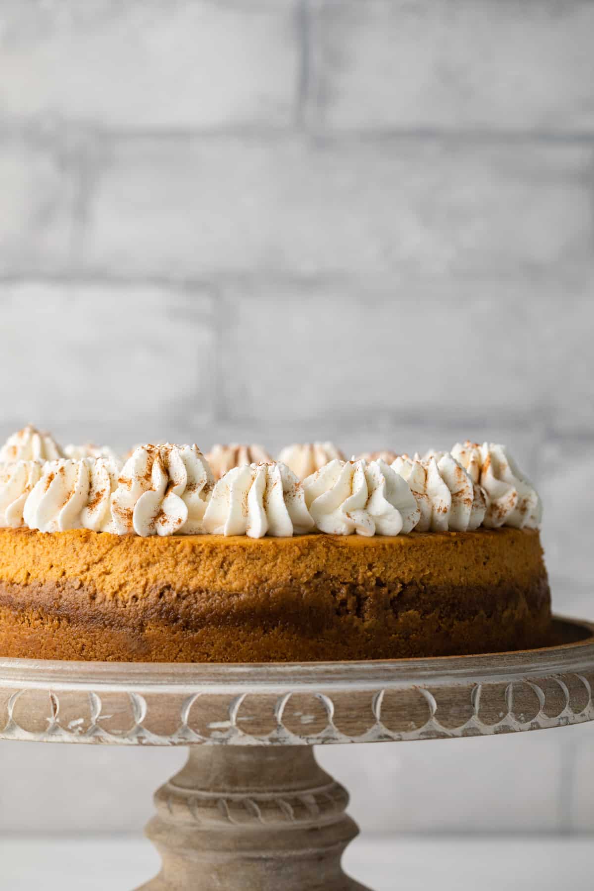 Side view of pumpkin cheesecake on wooden cake stand