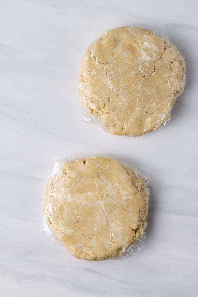 Two discs of pastry dough wrapped in plastic