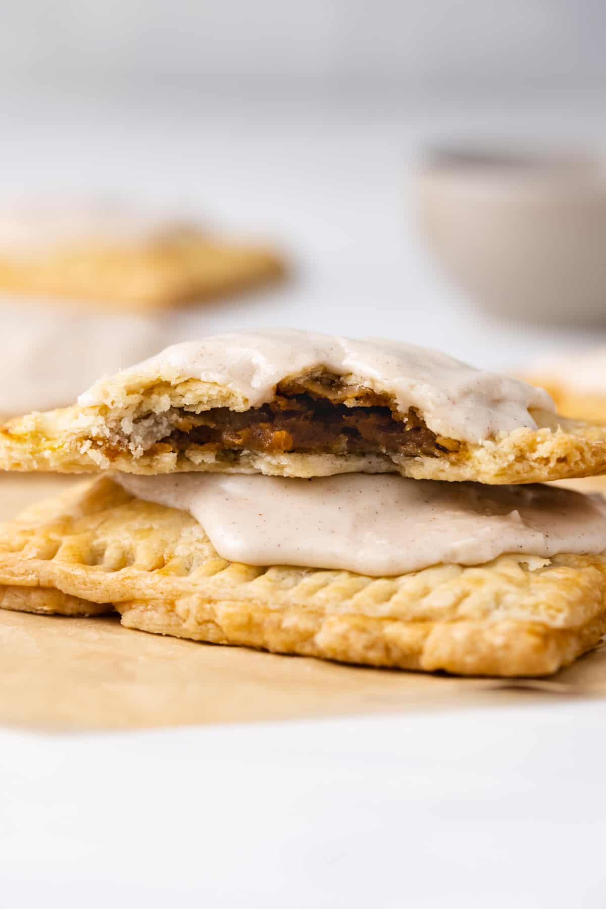 Two pumpkin pie pop tarts with cinnamon glaze, the top one missing a few bites