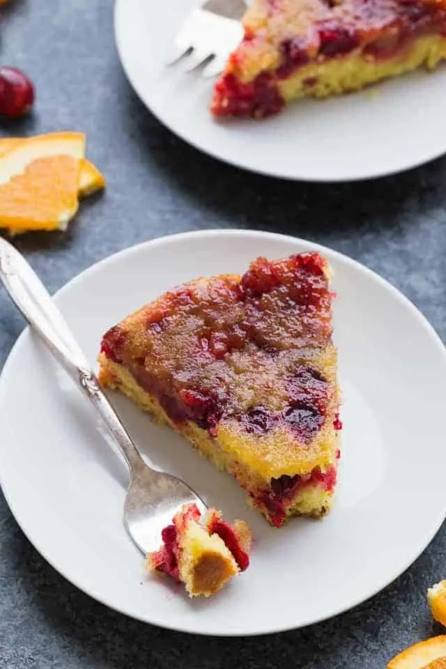 A slice of Cranberry Orange Upside Down Cake on a plate with a fork taking a bite out.