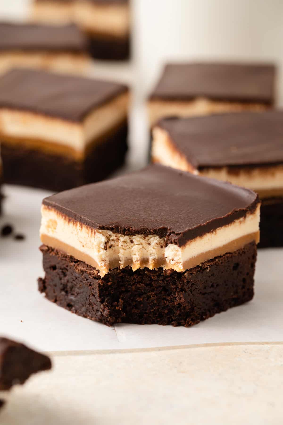 Above view a fudgy chocolate brownie with layers of gooey caramel, chewy nougat, and chocolate ganache over the top.