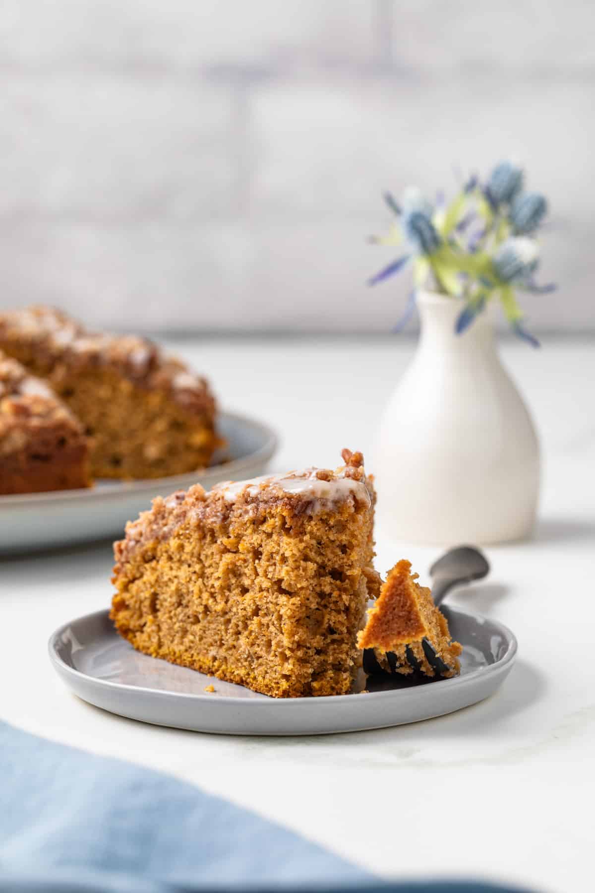 Slice of sweet potato coffee cake on plate with fork taking a bite out.