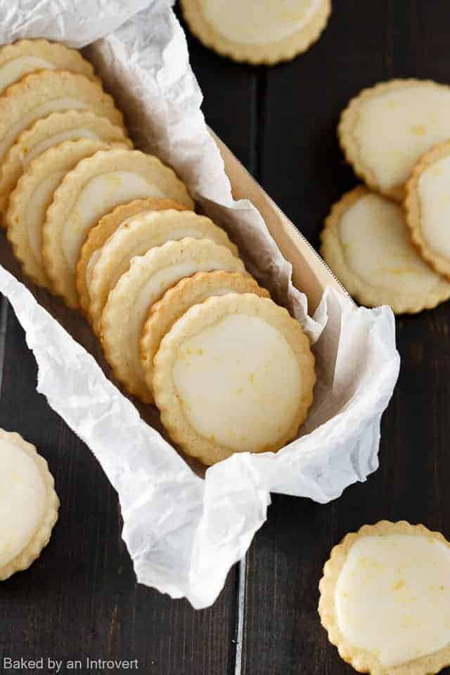 iced Meyer lemon cookies in a box with parchment paper