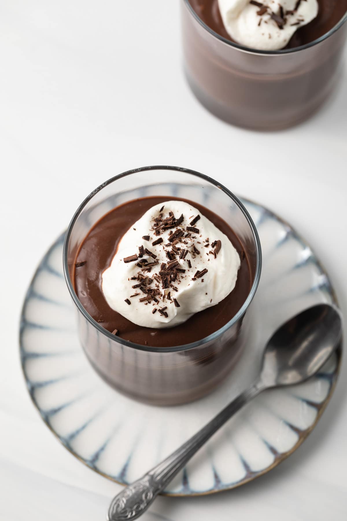 Chocolate pudding in a glass cup topped with whipped cream.