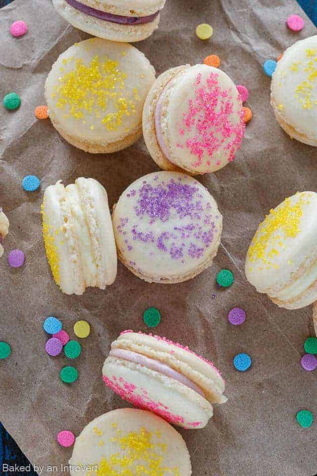 Overhead view of Easter cheesecake macarons on brown paper with sprinkles.