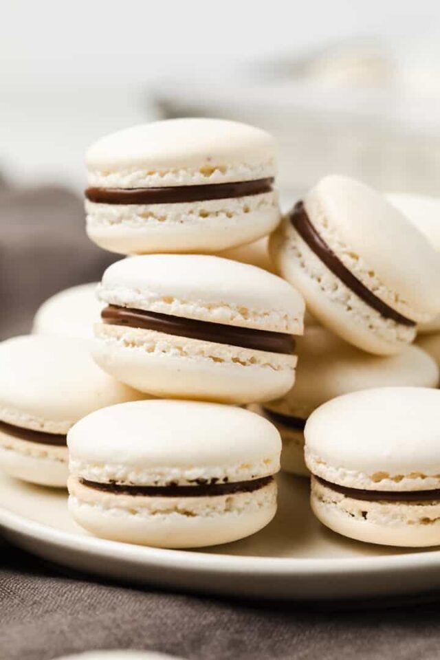 french macarons stacked on a white plate with brown napkin underneath
