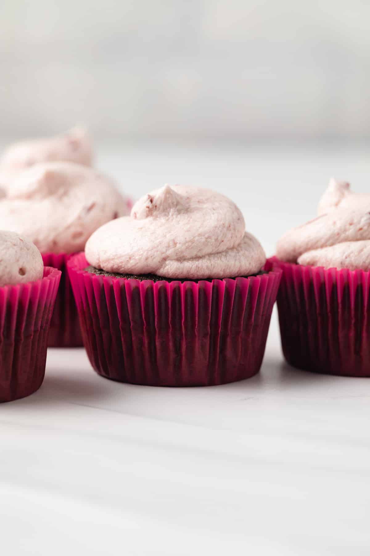 Chocolate cherry cupcakes on white tabletop.