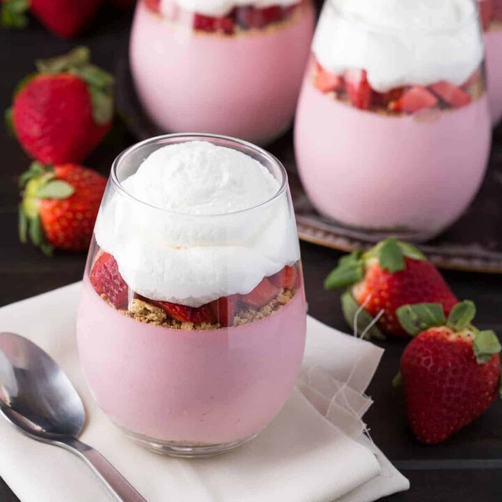 Strawberry cheesecake mousse in glass cups topped with whipped cream.