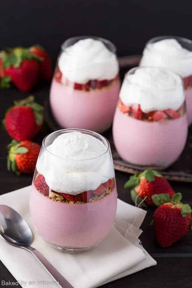 Strawberry cheesecake mousse in glass cups topped with whipped cream.