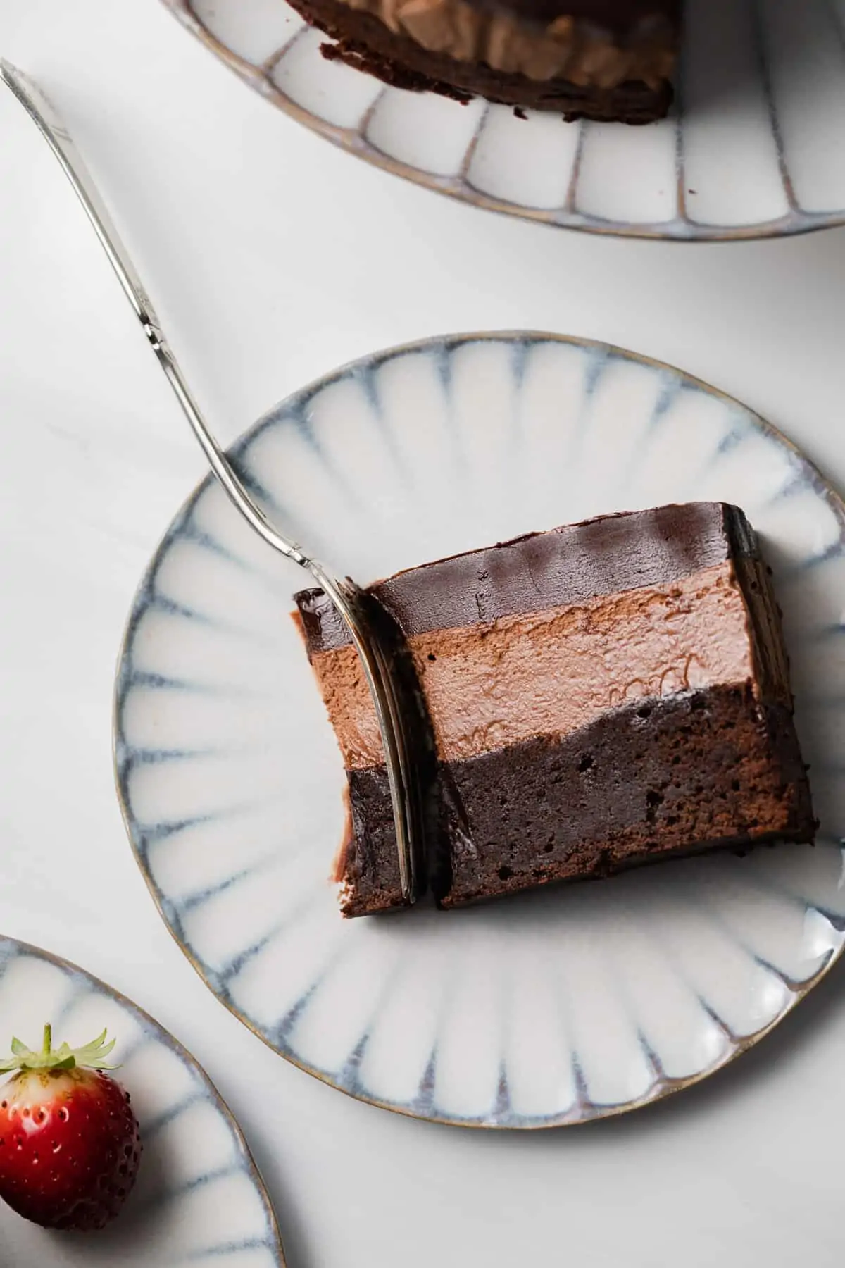 slice of triple chocolate mousse cake with fork taking a bite out