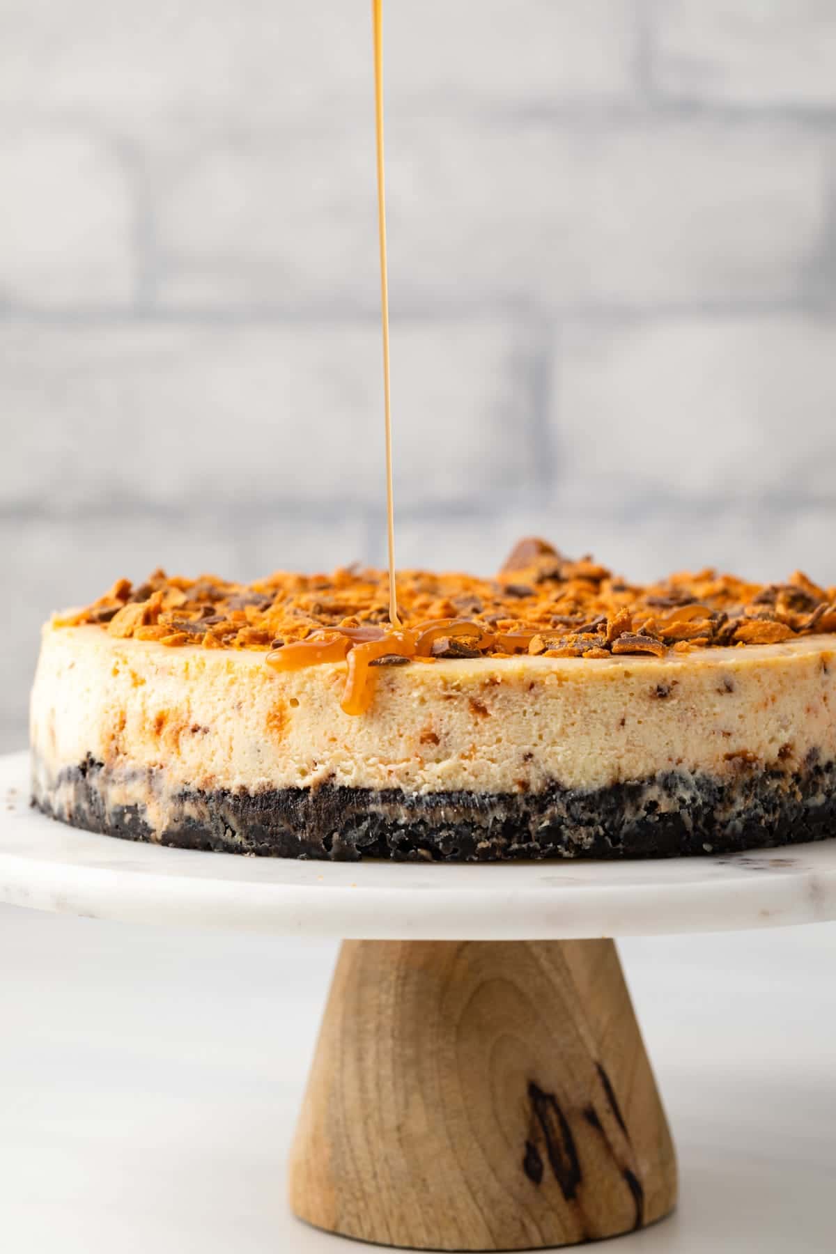 Butterfinger cheesecake on cake stand.