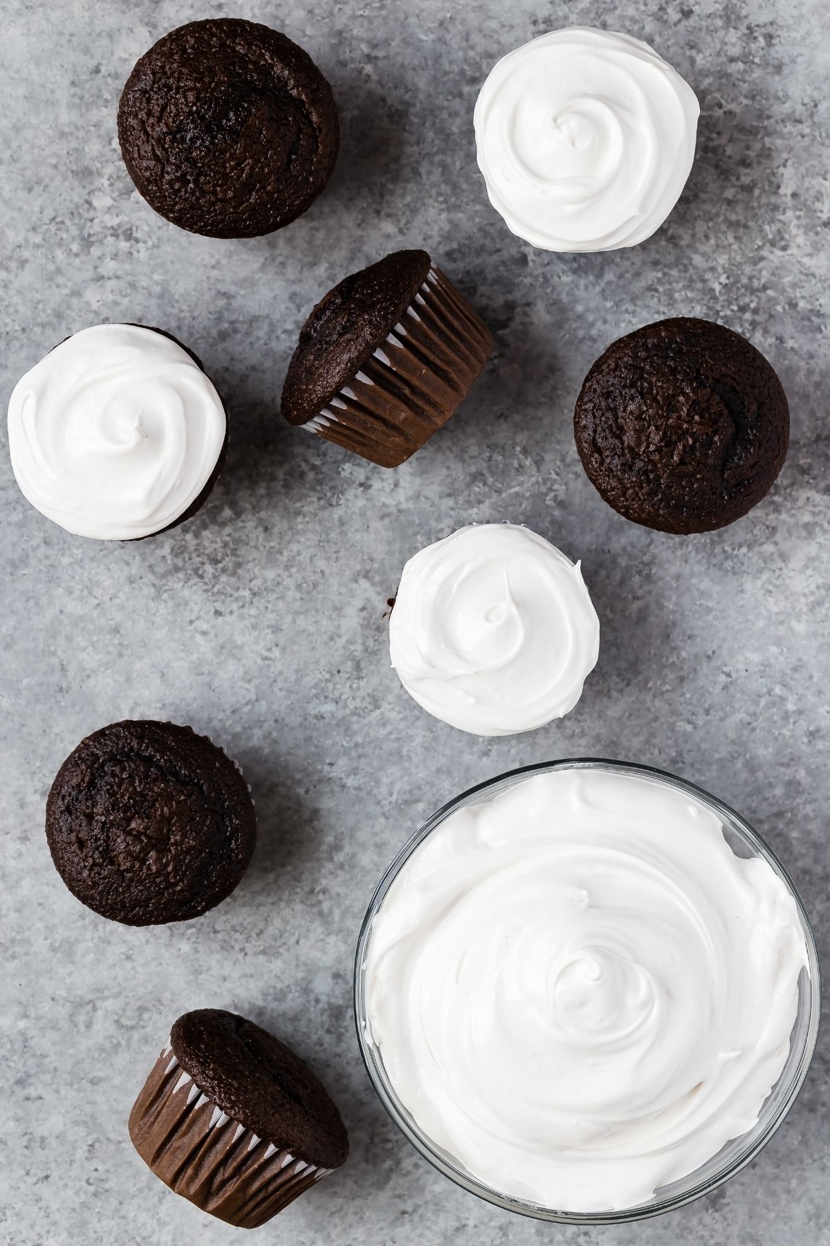 Overhead view of seven minute frosting in a glass bowl and on chocolate cupcakes.