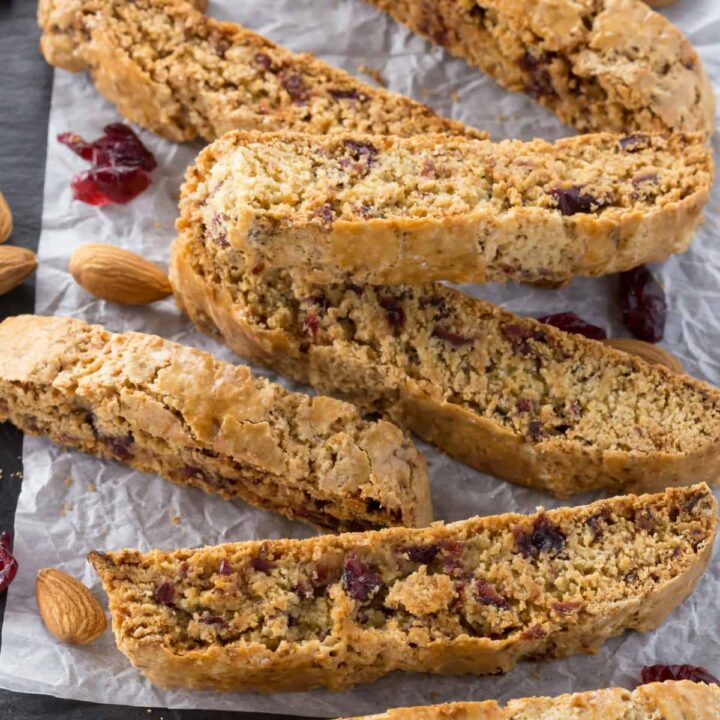 high angled view of cherry almond biscotti on a slate platter with white parchment paper