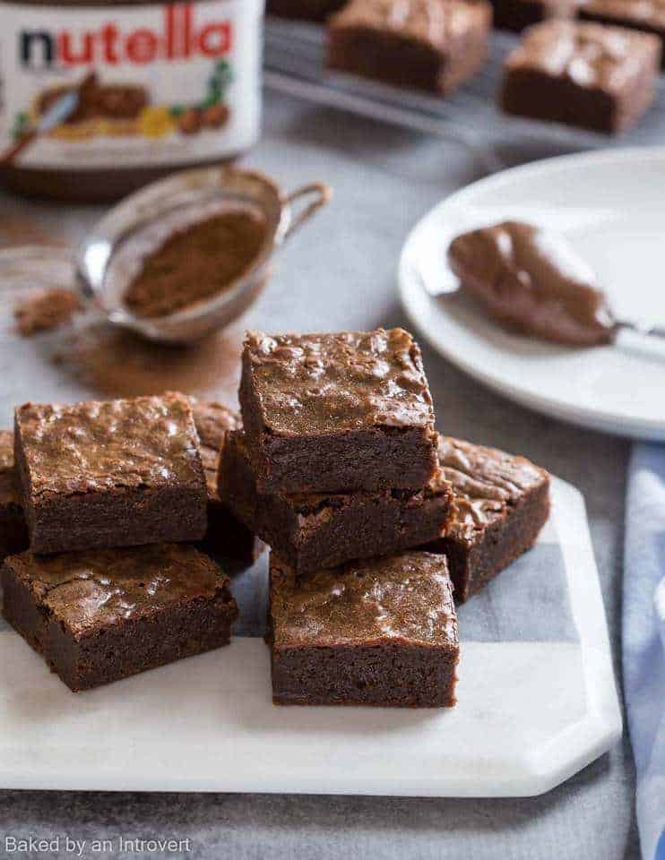 Nutella Brownies stacked on a white cutting board.