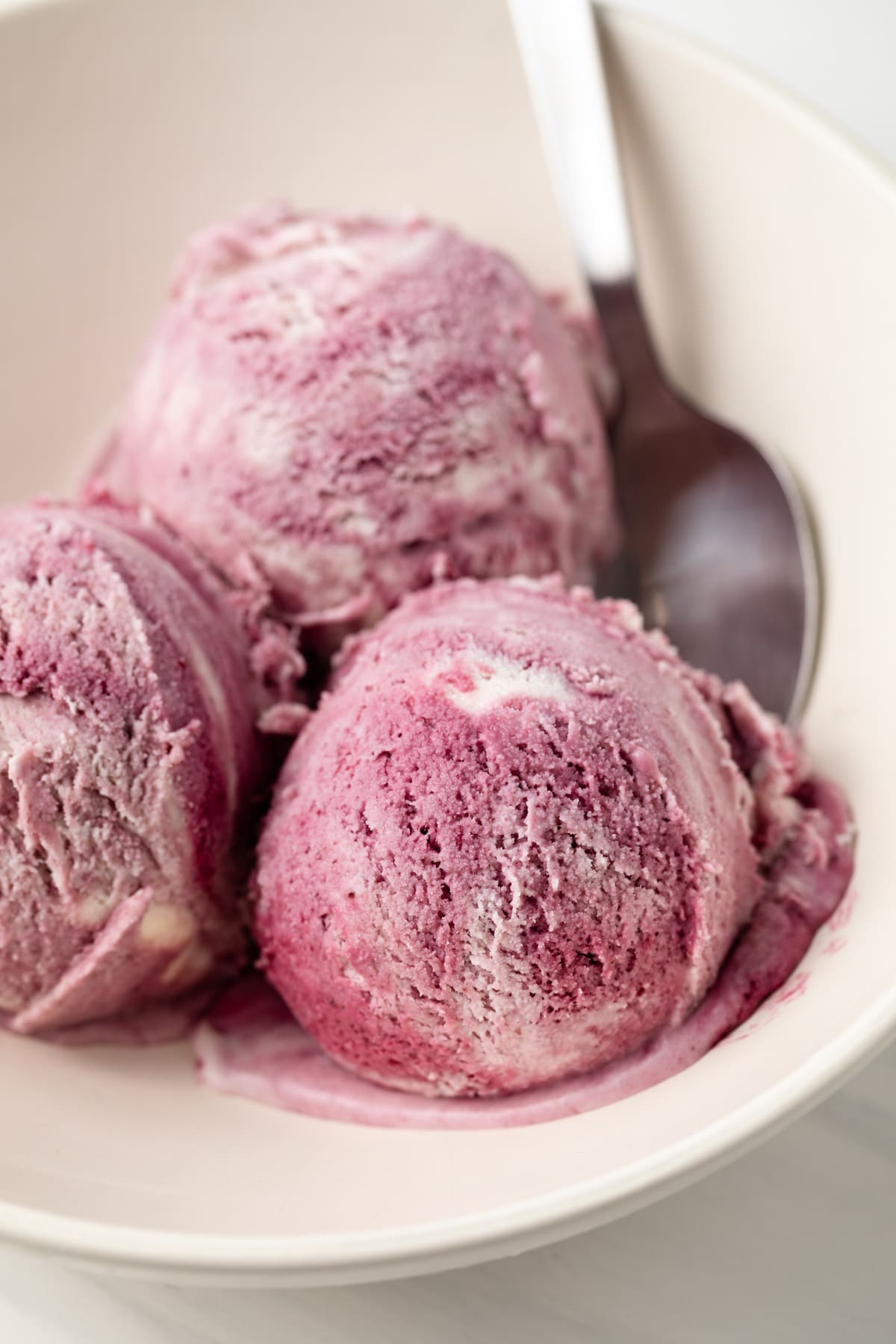 Close up of scoops of blackberry icecream in bowl.