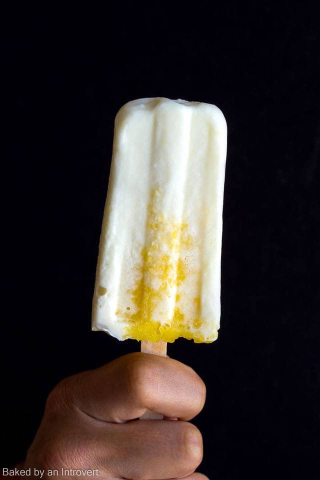 A hand holding a pina colada popsicle.