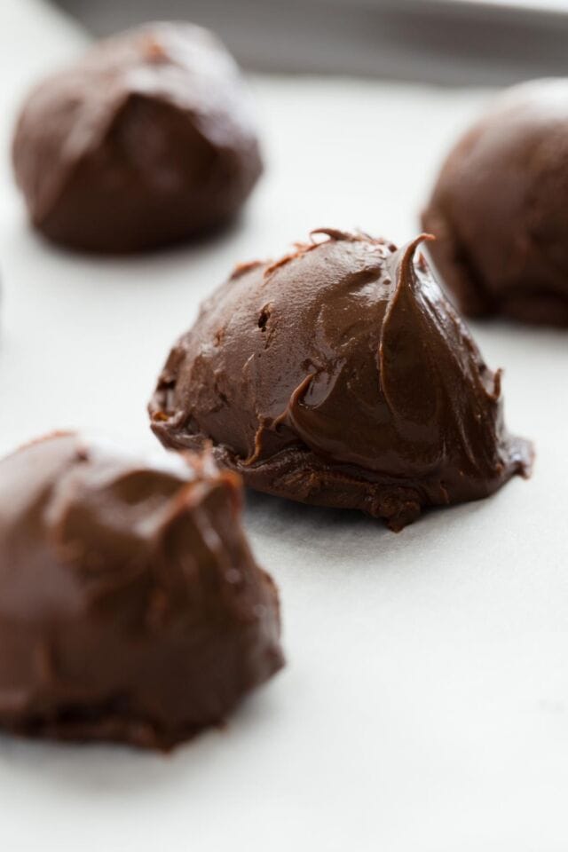 Balls of chocolate ganache lined on parchment paper.