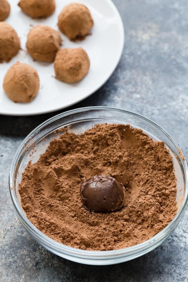 Ball of chocolate ganache in a bowl of cocoa powder.