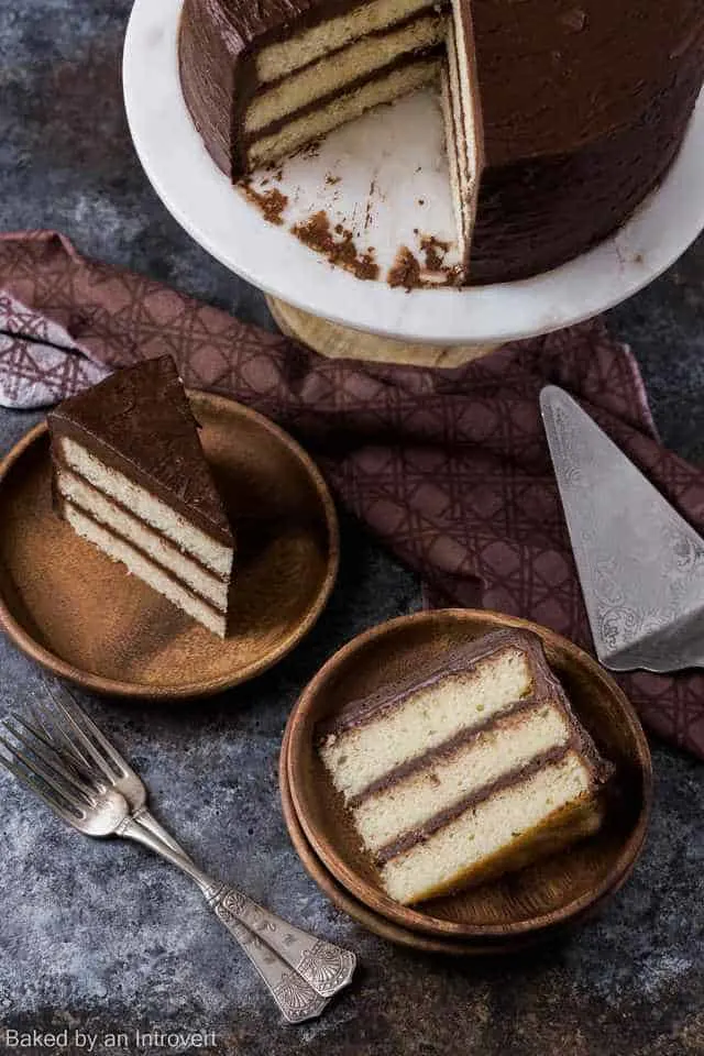 High angled view of vanilla cake slices with chocolate frosting on bamboo plates.