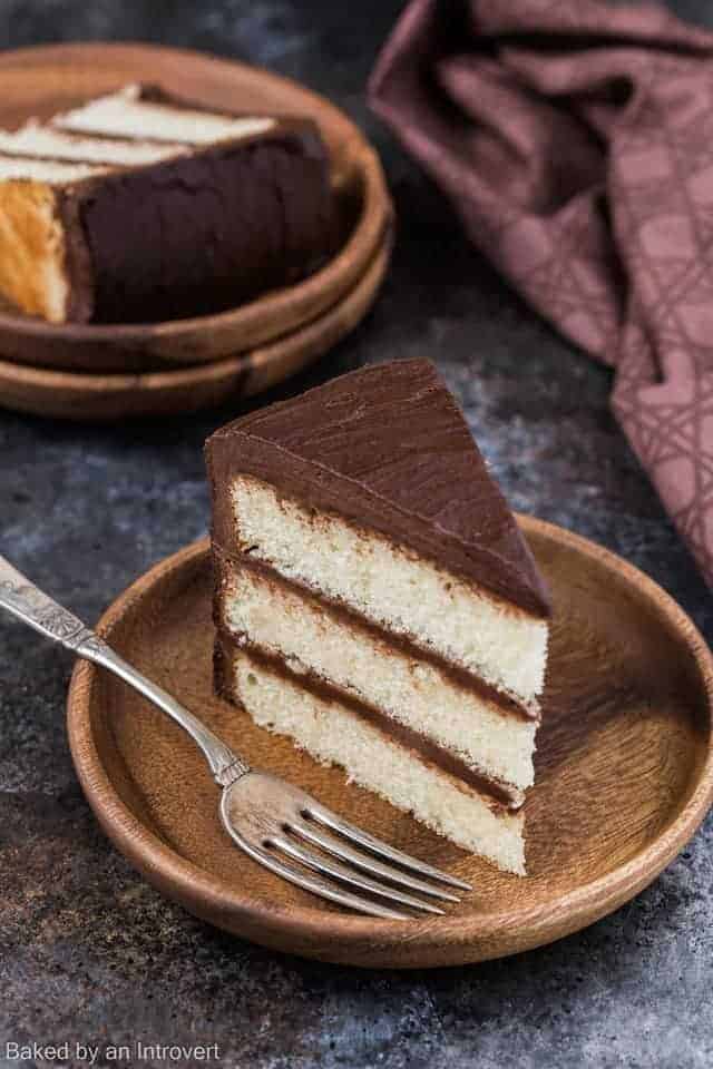 Three layer yellow cake with chocolate frosting on bamboo plates.