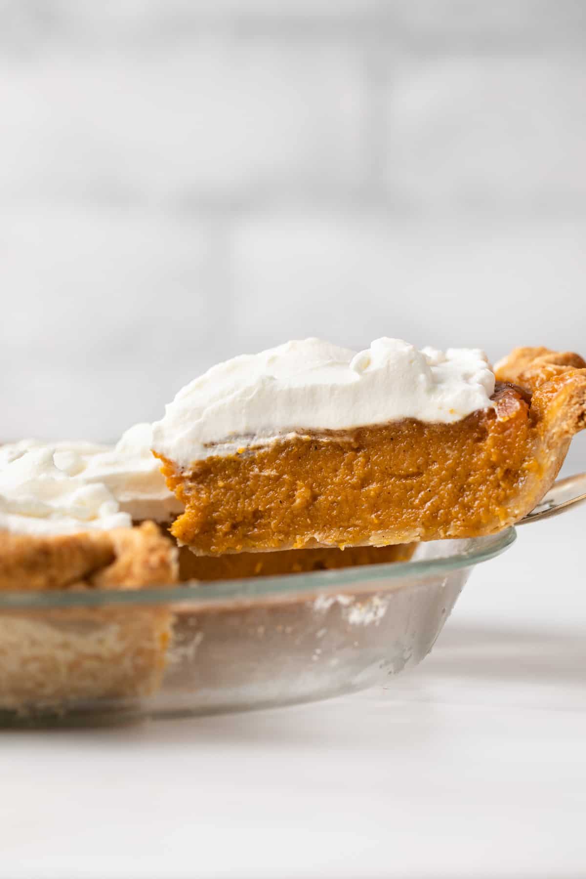 A slice on caramel sweet potato pie being served from the pan