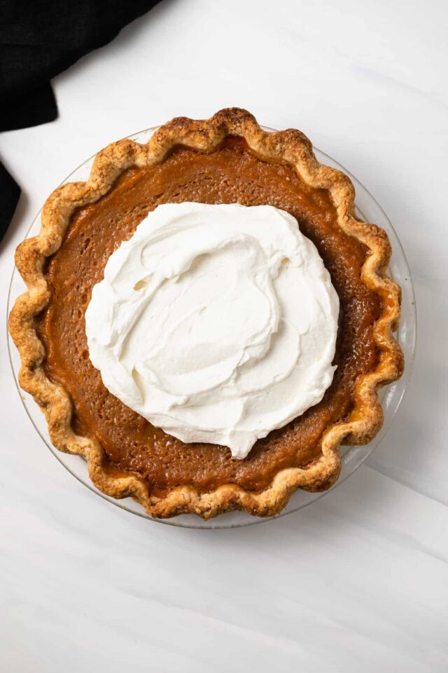 Whipped cream being spread on pie
