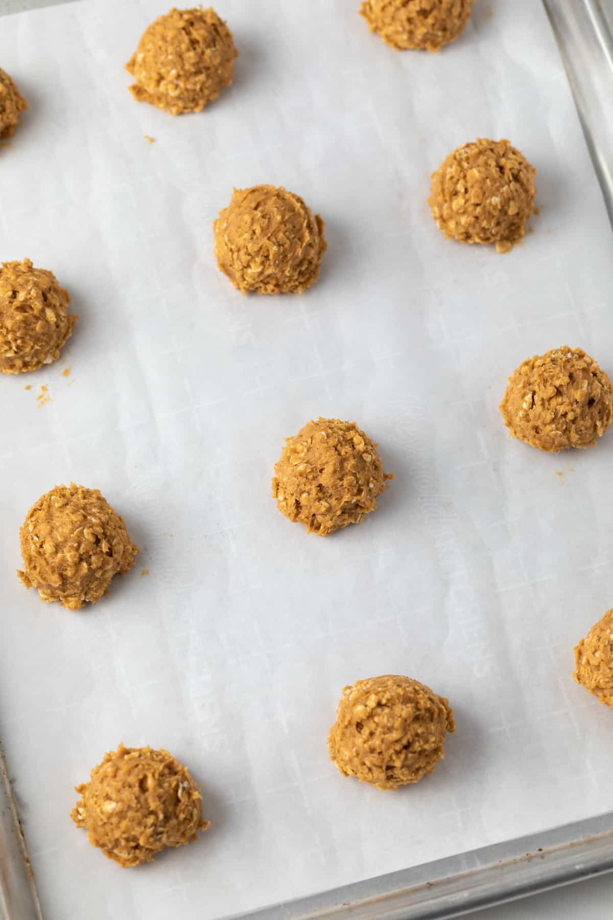 Unbaked pumpkin oatmeal cookie dough balls on baking sheet lined with parchment paper