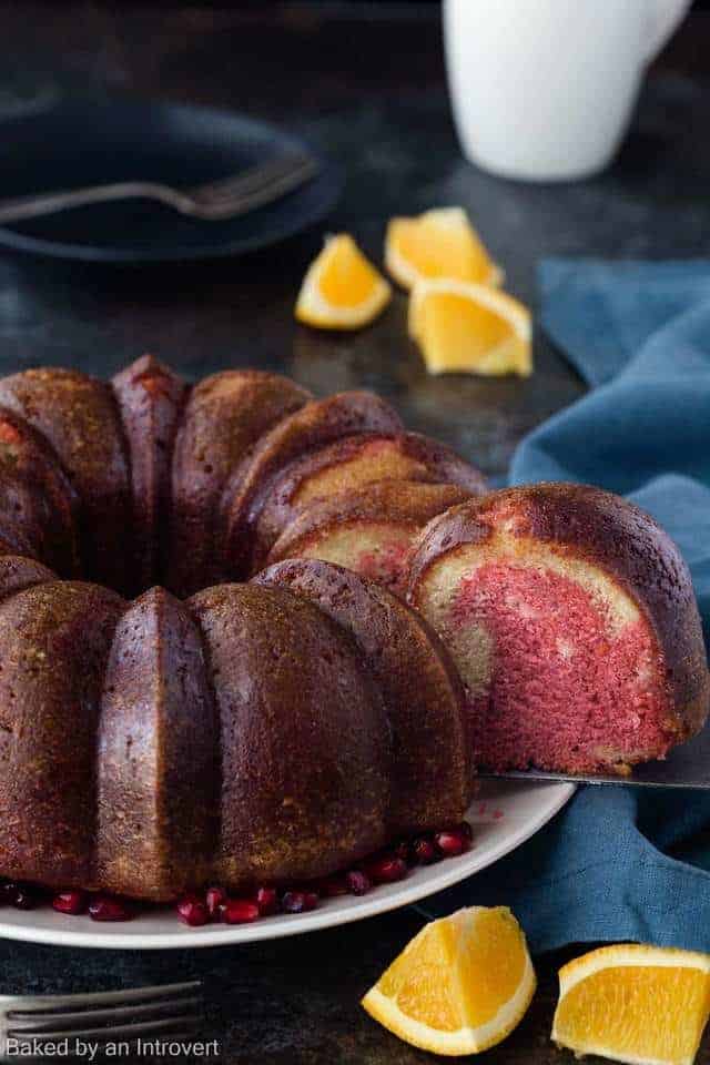 Tequila sunrise cake on a cream plate with a slice being taken out.