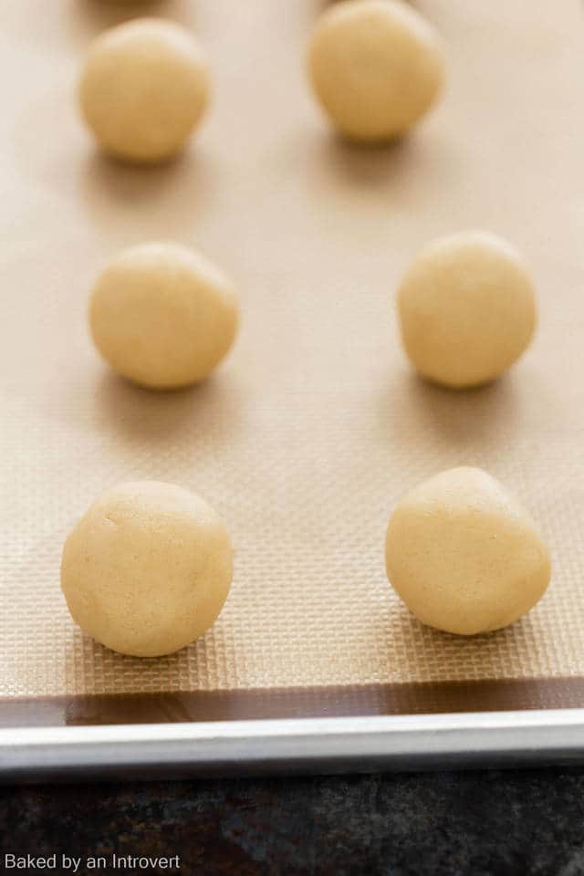 Moon pie cookie dough balls on a baking sheet lined with a silicone mat.