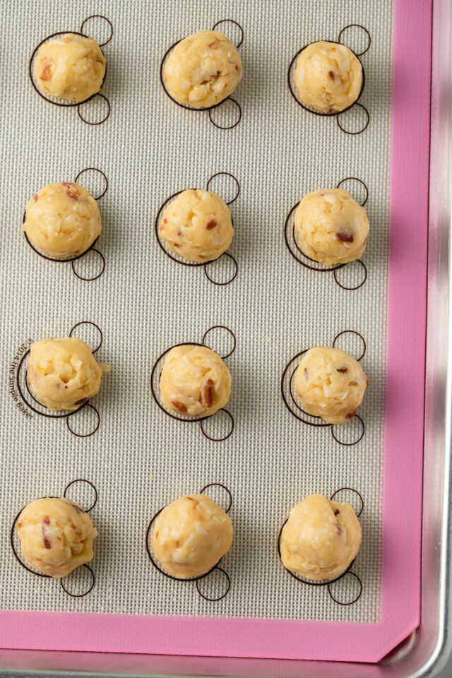 Balls of bacon garlic gougeres dough on a baking sheet