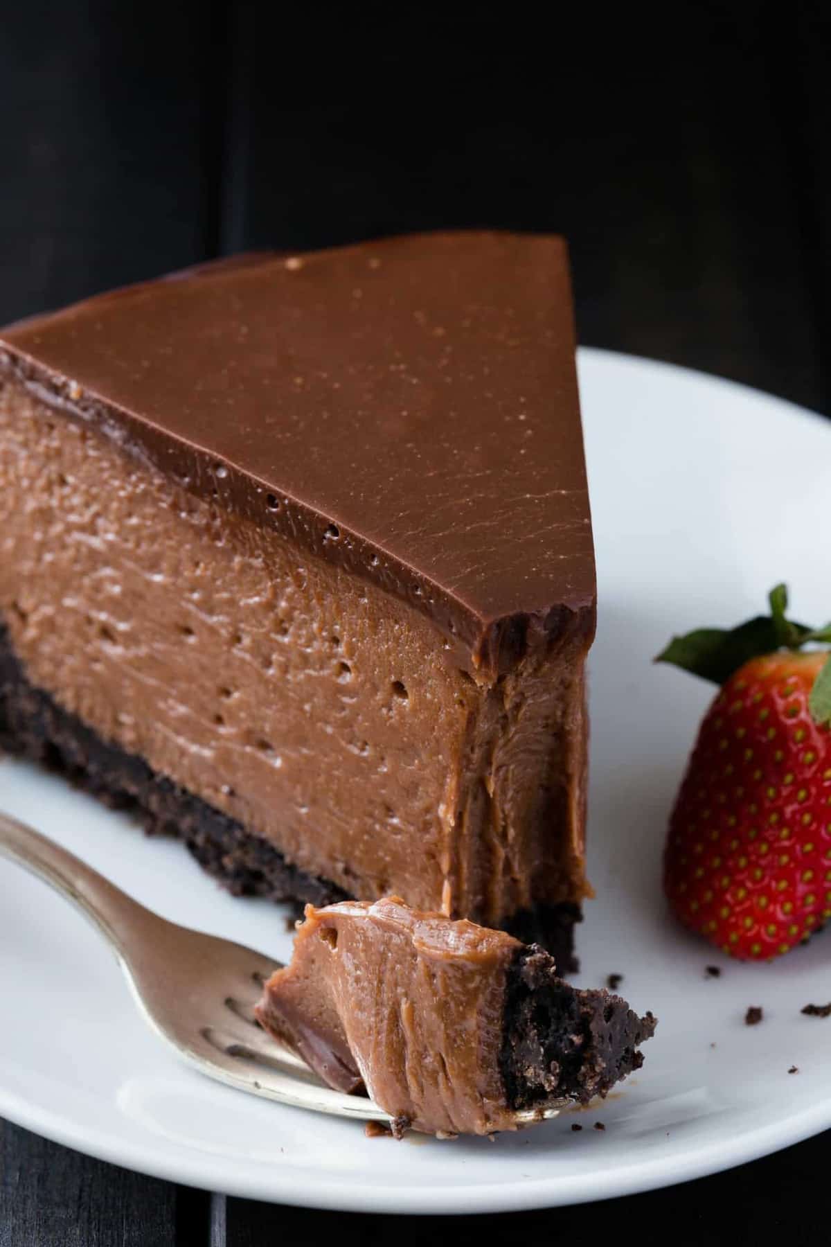 A slice of Nutella cheesecake on a white plate with fork holding a small bite.