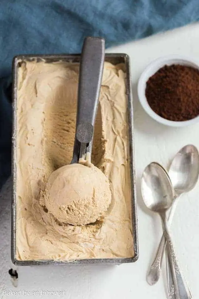 Overhead view of homemade ice cream flavored with coffee in a loaf pan with an ice cream scoop.