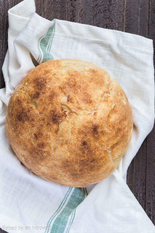 Loaf of rustic homemade slow cooker bread on a white towel.