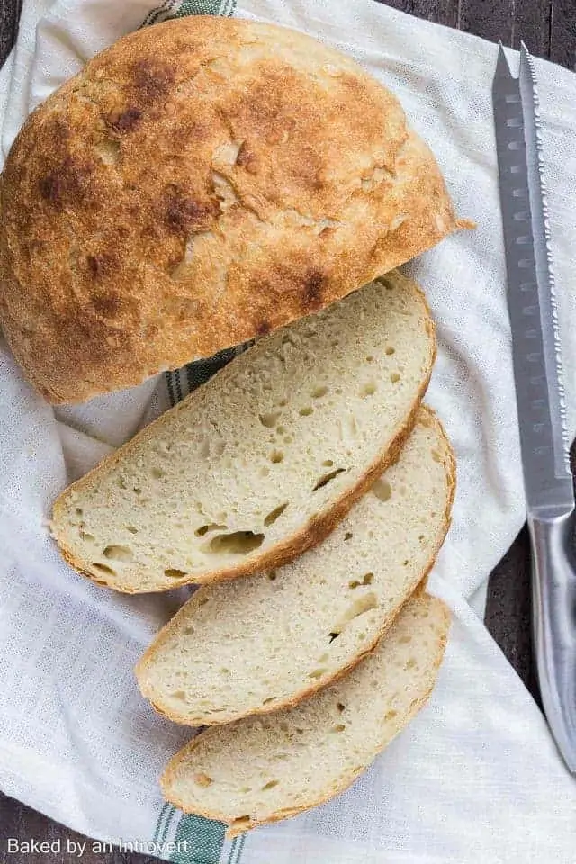 Homemade Slow Cooker Bread sliced on a white towel next to a knife.