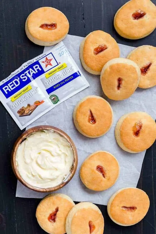 overhead view of buttery jam biscuits with a bowl of butter and pack of yeast