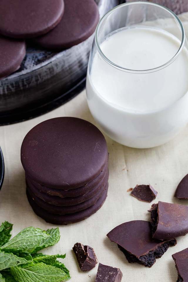 High angle view of a stack of thin mints next to a glass of milk.