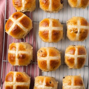Hot cross buns on a wire rack with parchment paper.