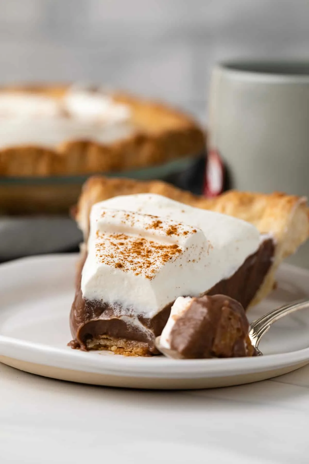 A slice of chocolate pie with chai cream topping on a plate