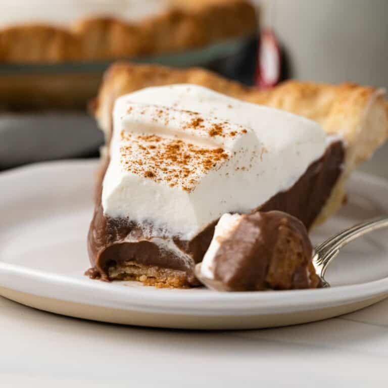 A slice of chocolate pie with chai cream topping on a plate