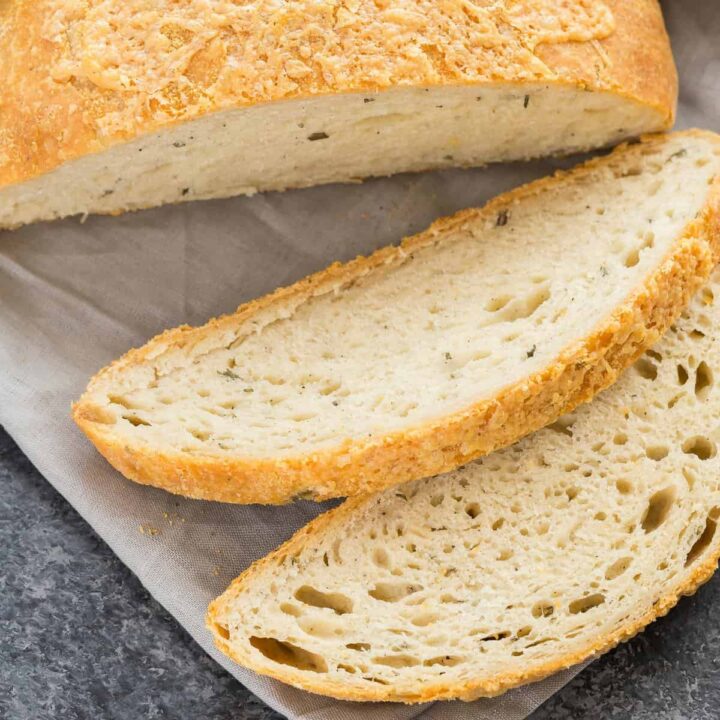 A loaf of Rosemary Cheese Bread with two slices cut out.