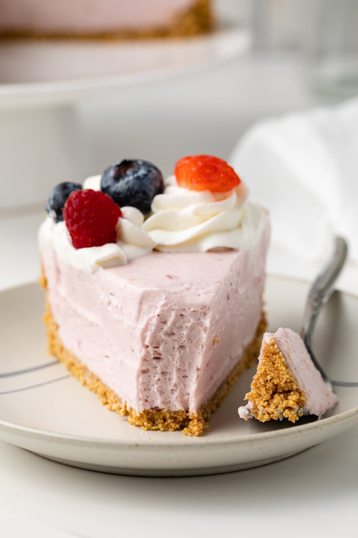 Slice of no bake berry cheesecake with a fork bite taken out.
